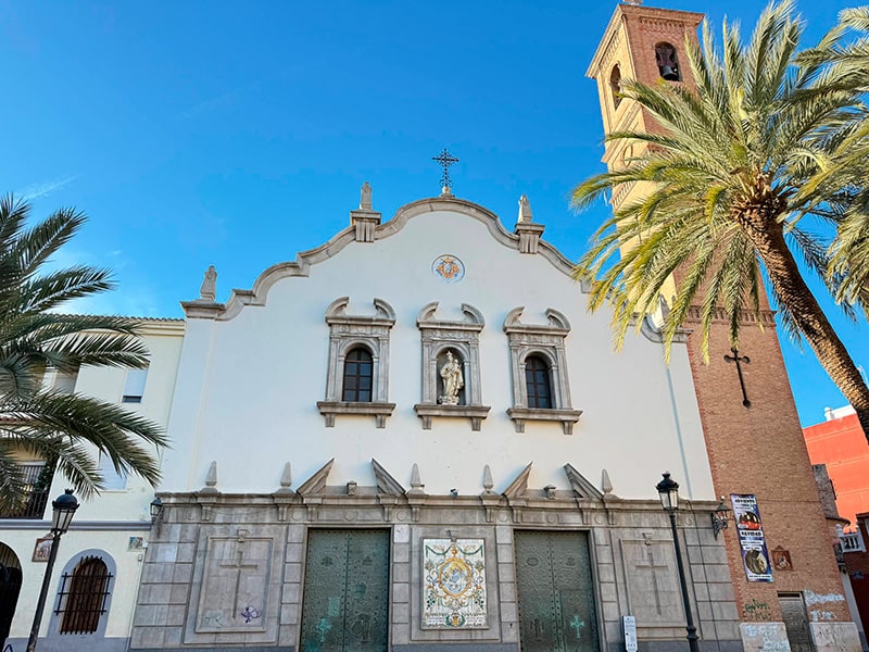 Фасад церкви с колокольней и пальмами на площади в районе Кабаньял (Валенсия).