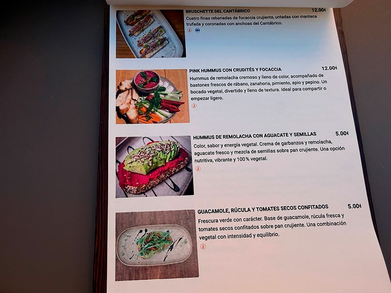 Страница меню с фотографиями закусок и описаниями блюд на испанском языке в заведении района Кабаньял (Валенсия).