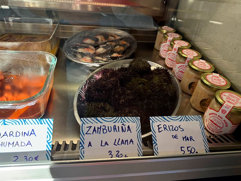 Витрина с морепродуктами в баре рынка: морские ежи (erizos de mar), морские ракушки (zamburi&ntilde;a) и ценники (Кабаньял, Валенсия).