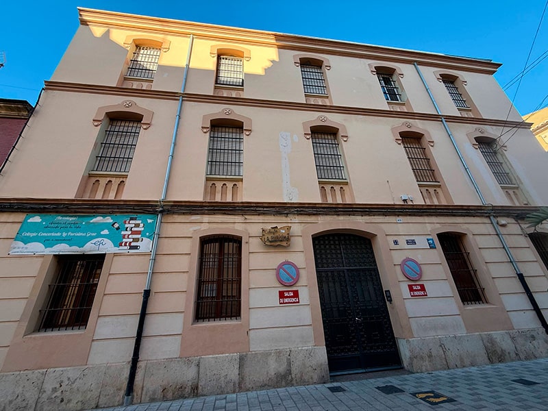 Фасад здания школы Colegio La Pur&iacute;sima с решётками на окнах и табличками у входа в районе Кабаньял (Валенсия).