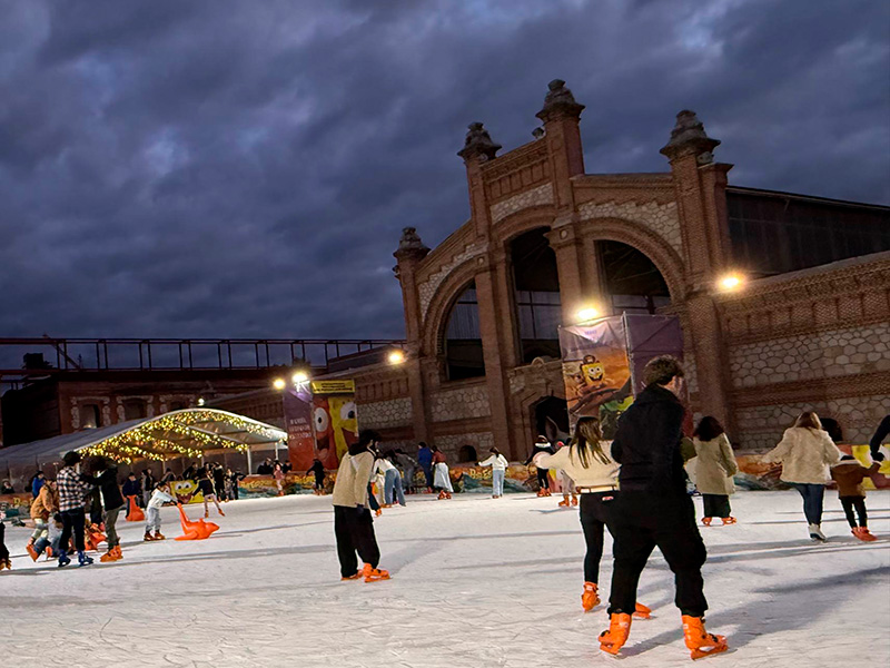 Каток у Matadero Madrid в районе Arganzuela (Legazpi): вечернее катание на коньках на фоне исторического здания и праздничных огней