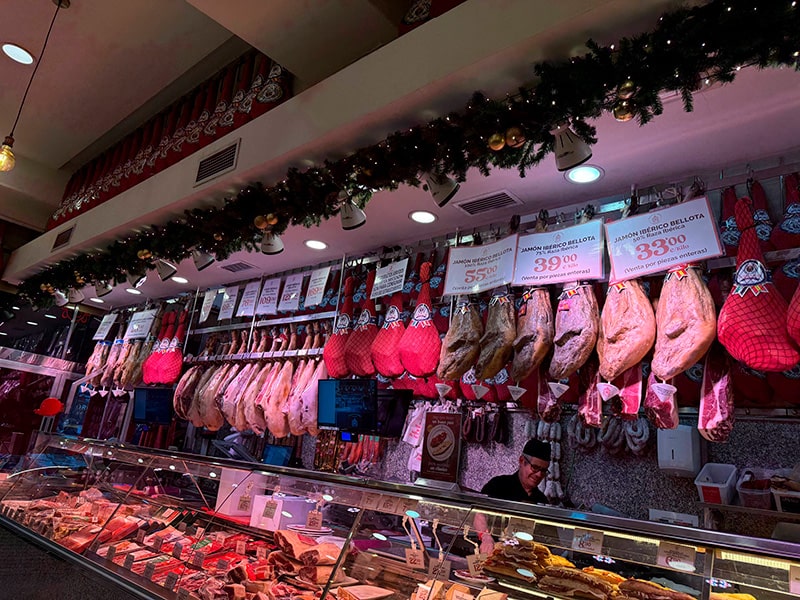 Витрина Museo del Jamón с подвешенными окороками и нарезками хамона