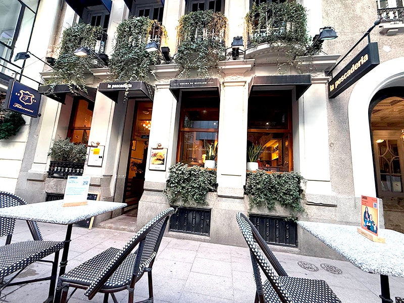 Фасад ресторана La Pescadería в центре Мадрида с уличной террасой и столиками на тихой пешеходной улице