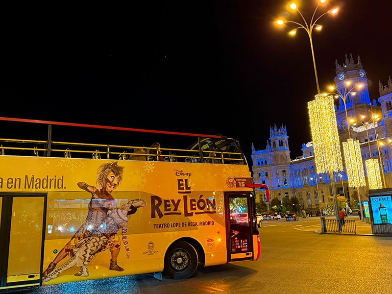 Туристический двухэтажный автобус с рекламой мюзикла El Rey León на Plaza de Cibeles в Мадриде, на заднем плане подсвеченный Palacio de Cibeles и рождественская иллюминация  Название файла (транслит, без пробелов):