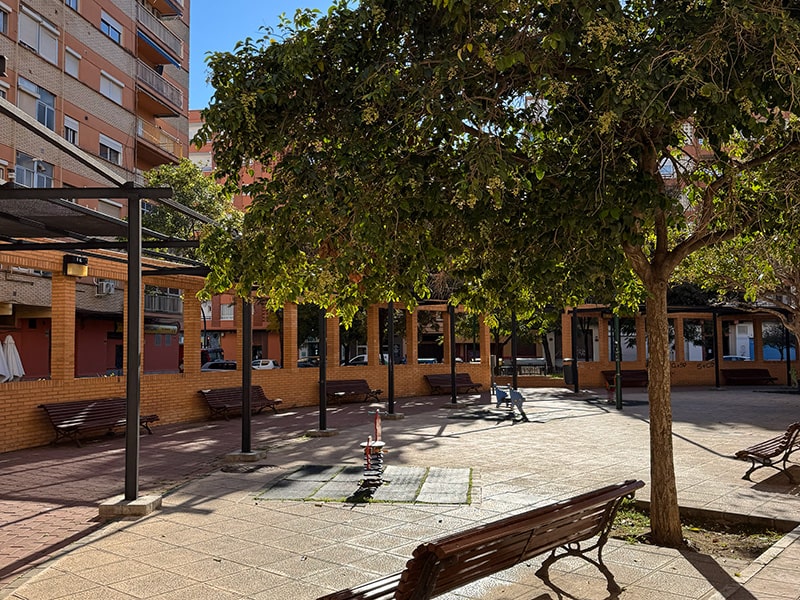 Спокойная внутренняя площадь с деревьями и скамейками в районе Benicalap в Валенсии