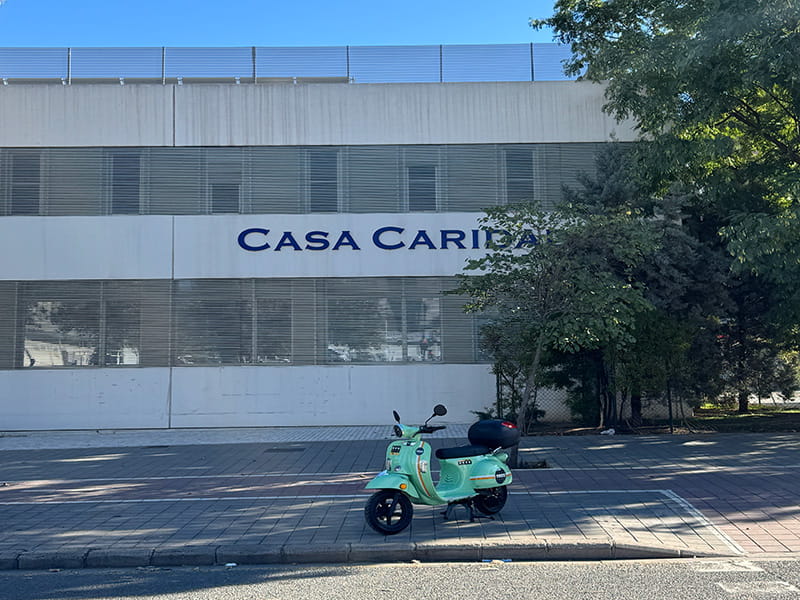 Здание с вывеской &laquo;Casa Caridad&raquo; и припаркованный мятный скутер на улице в районе Беникалап, Валенсия, Испания