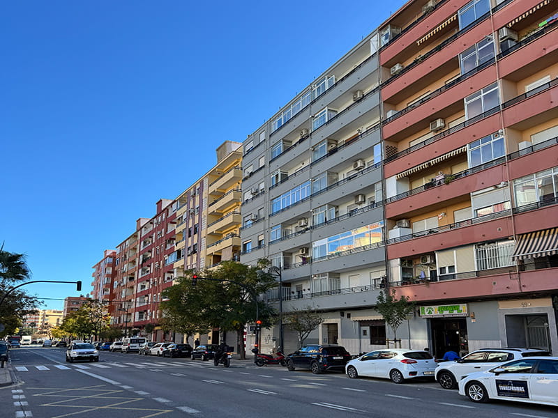 Широкая улица с многоэтажными жилыми домами и припаркованными машинами в районе Беникалап, Валенсия, Испания