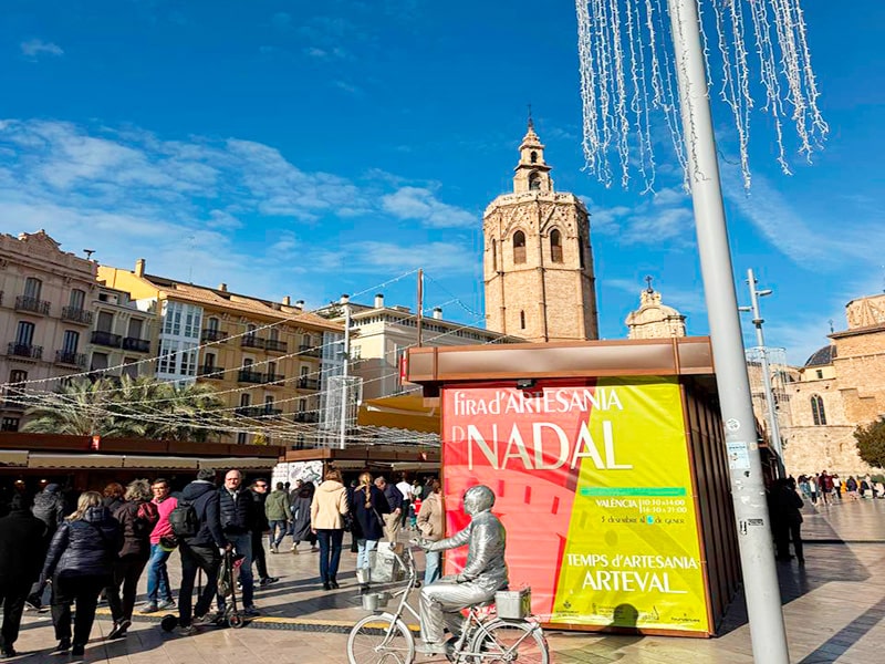 Рождественская ярмарка ремёсел на Plaza de la Reina в Валенсии и башня Мигелете на фоне