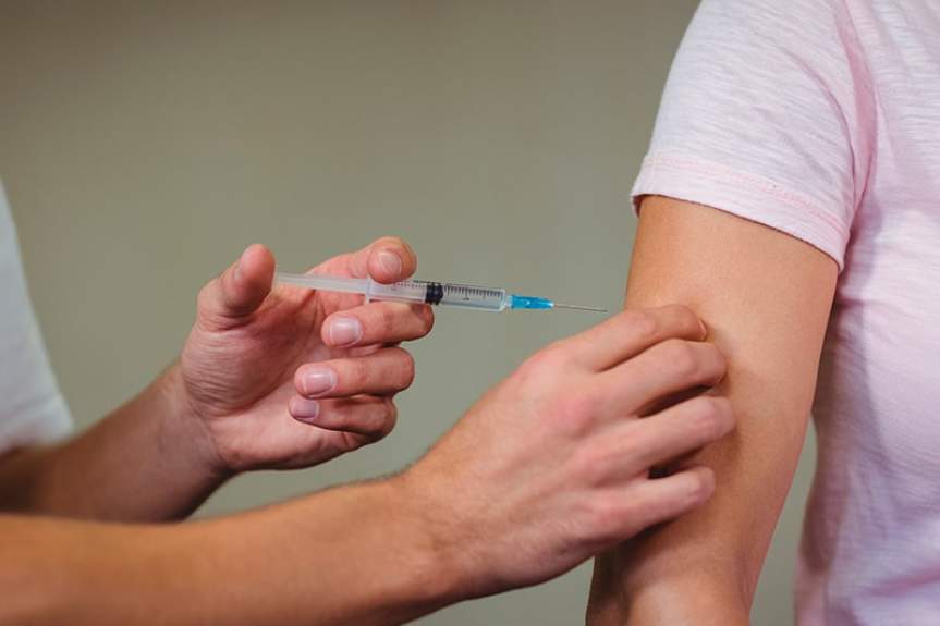 Медработник делает укол в плечо взрослому пациенту во время вакцинации